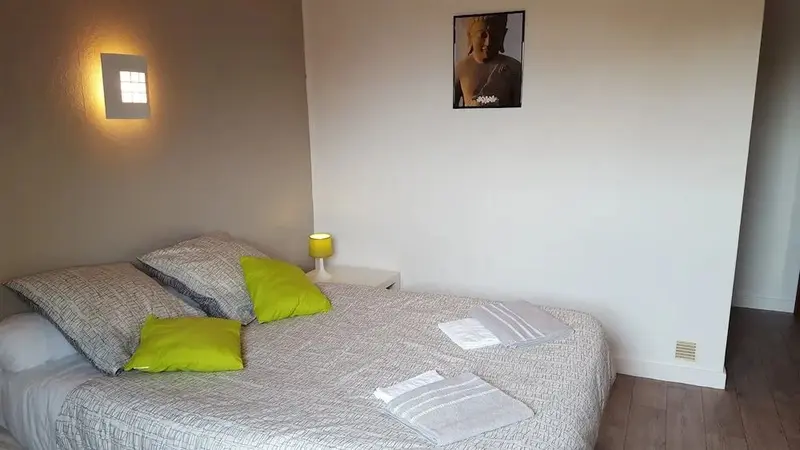 Une chambre lumineuse avec un grand lit recouvert d'une couette et de coussins.