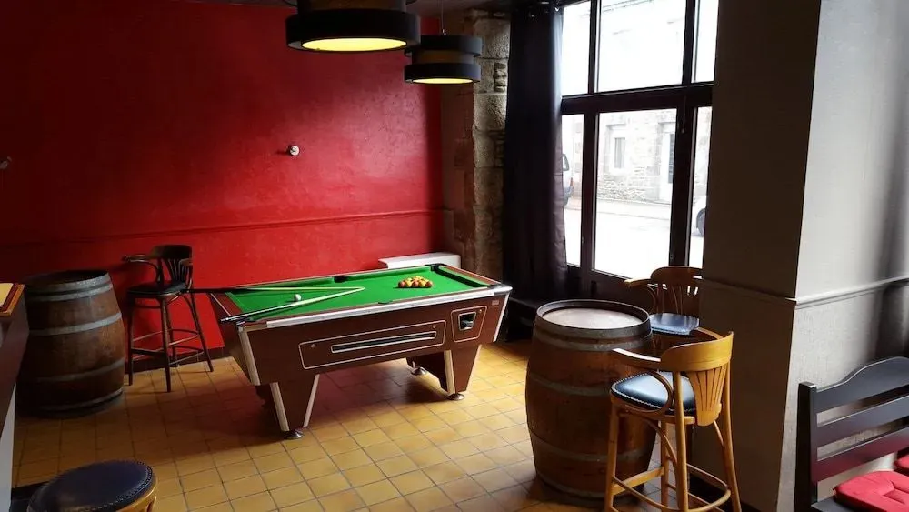 Une table de billard se trouve dans une pièce aux murs rouges et au sol carrelé.
