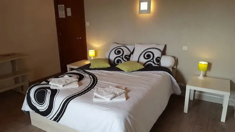 Une chambre lumineuse avec un grand lit recouvert d'une couette à motifs.