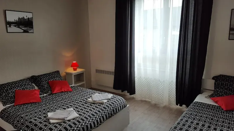 Une chambre avec deux lits doubles et une fenêtre.