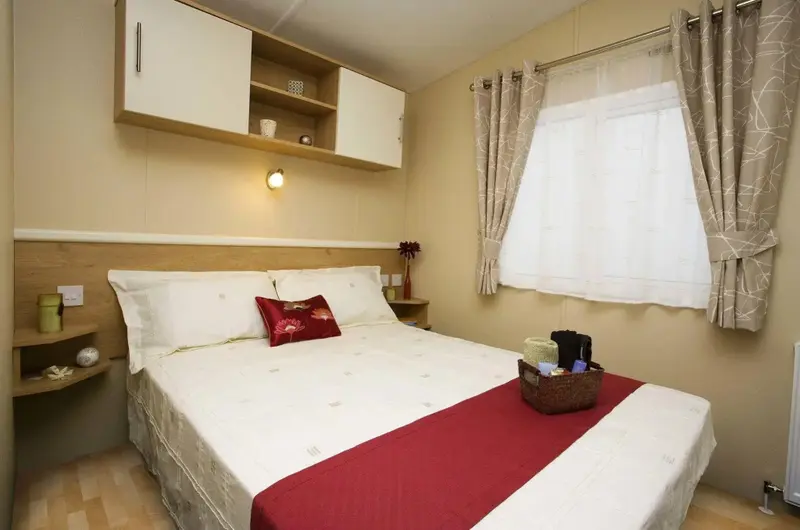 Une chambre lumineuse avec un grand lit et des rangements muraux.