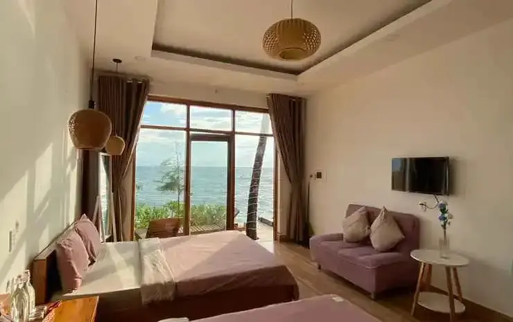 Une chambre lumineuse avec un grand lit et un coin salon donnant sur la mer.