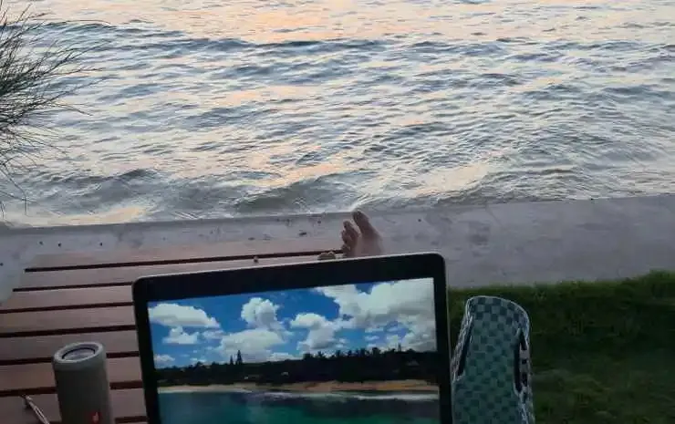 Une personne se repose sur une table en bois face à la mer.