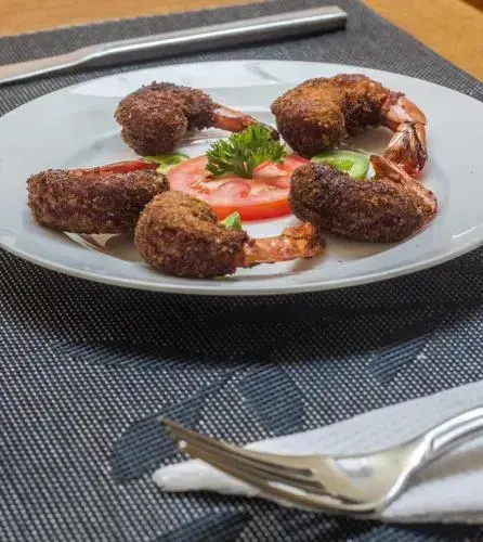 Assiette de crustacés panés, accompagnée de légumes et de tomates.
