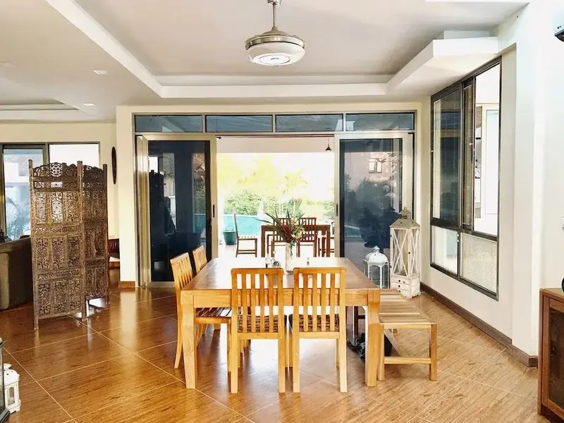 Une grande salle à manger lumineuse s'ouvre sur une terrasse avec vue sur une piscine.