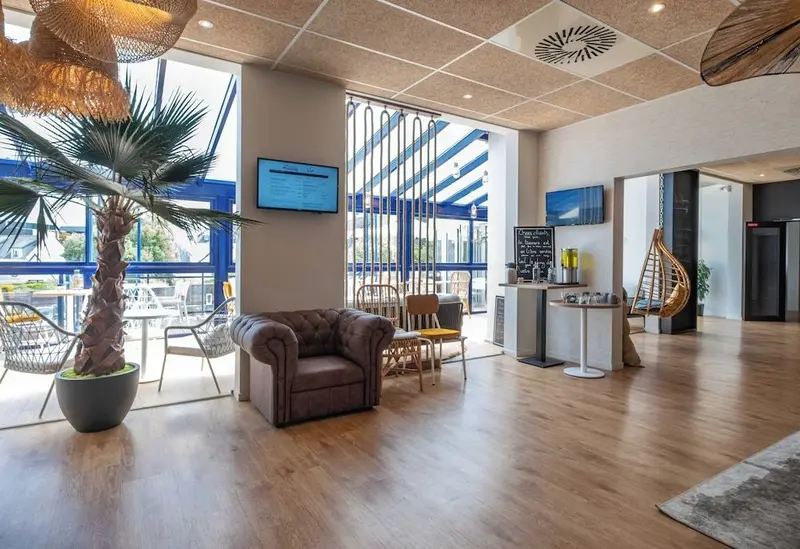 Un espace de détente intérieur avec des fauteuils et une plante tropicale près d'une grande baie vitrée.