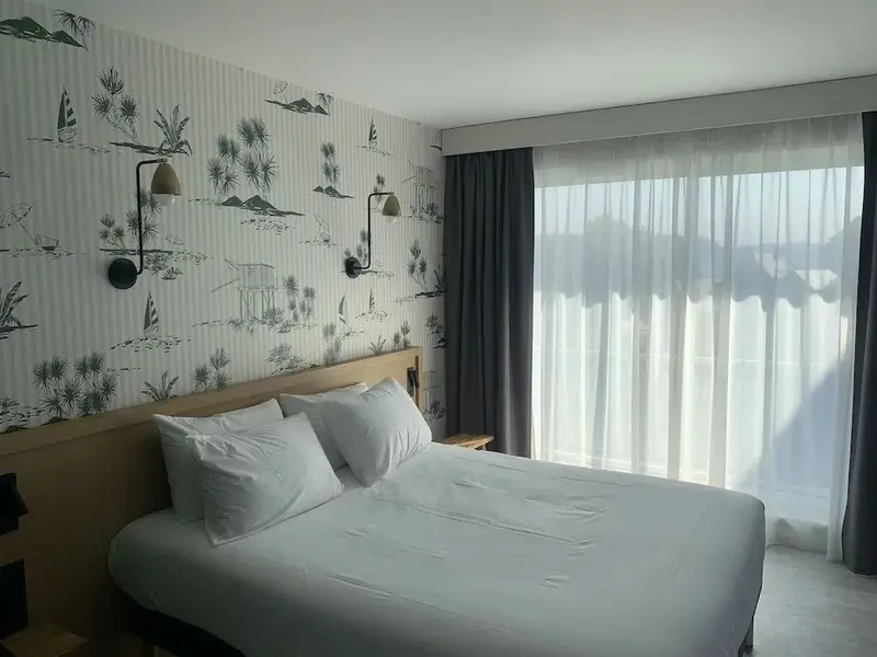Une chambre lumineuse avec un grand lit et un papier peint décoratif.