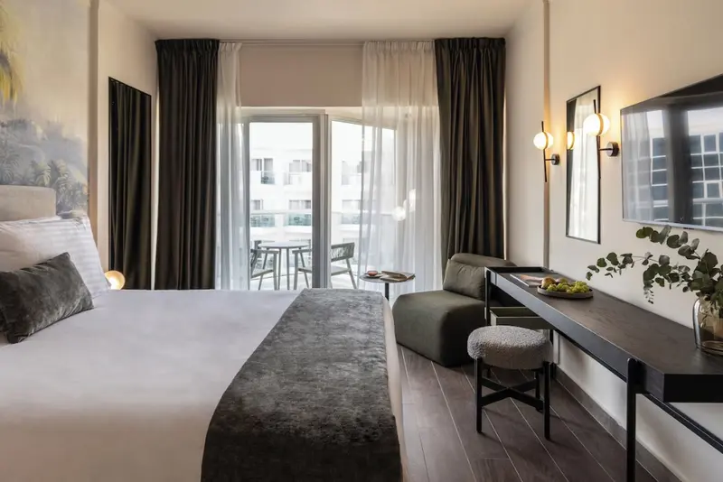 Une chambre lumineuse avec un grand lit et un accès à un balcon.