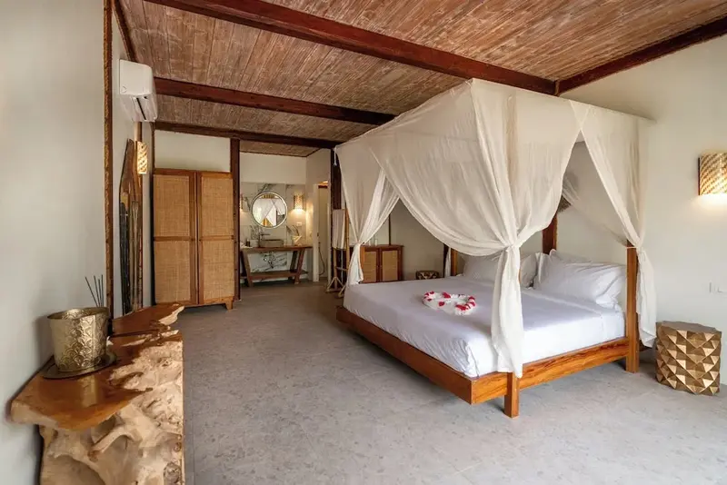 Une chambre lumineuse avec un lit à baldaquin en bois.