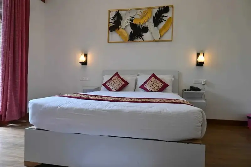 Une chambre lumineuse avec un grand lit recouvert d'une courtepointe blanche et de coussins décoratifs.