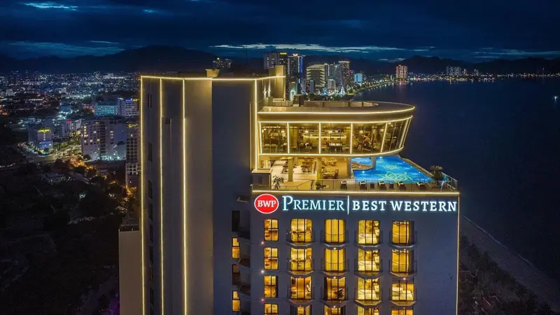 Vue nocturne d'un immeuble illuminé surplombant une ville côtière.