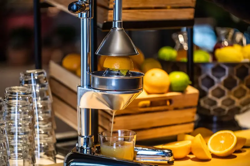 Un presse-agrumes en métal sert à extraire le jus d'une orange.