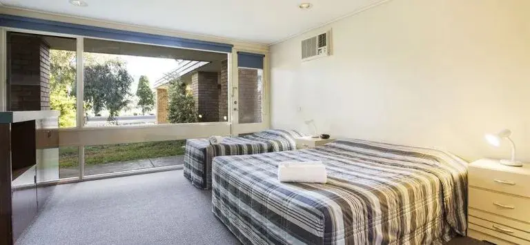 Une chambre lumineuse avec deux lits simples et une vue sur un jardin.