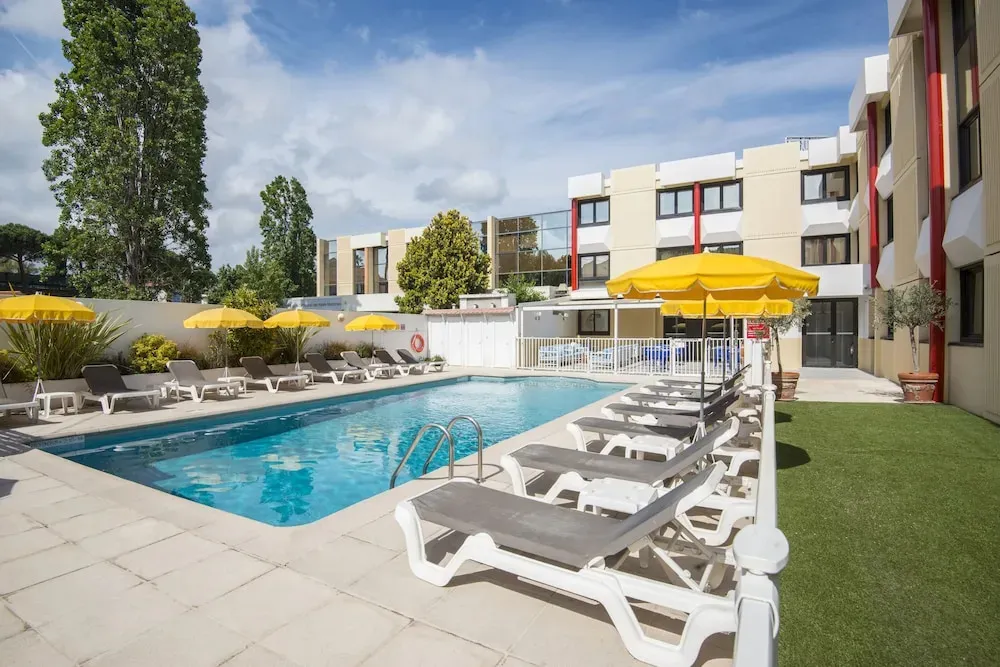 Une piscine ensoleillée avec des transats et des parasols.