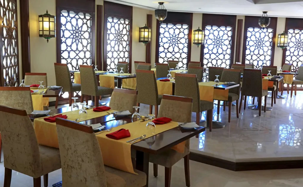 Une salle de restaurant lumineuse avec des tables dressées et des chaises.