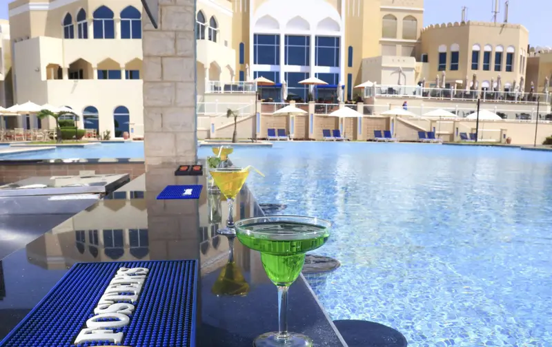 Des cocktails colorés sont servis au bord d'une piscine ensoleillée.