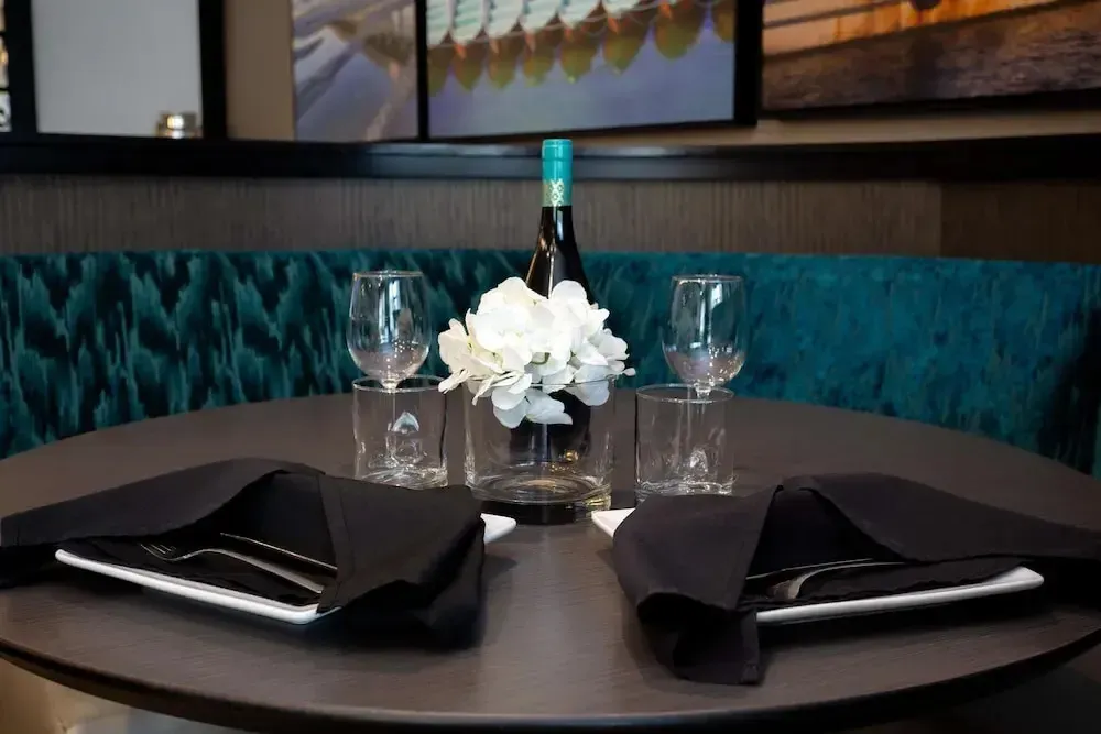 Une table ronde est dressée avec de la vaisselle et une bouteille de vin.