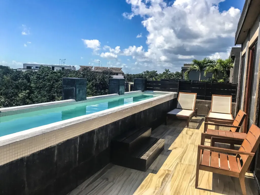 Terrasse avec piscine à débordement et chaises longues en bois.