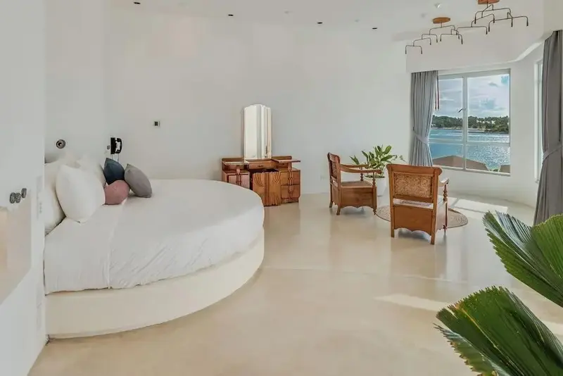 Une chambre lumineuse avec un grand lit rond et une vue sur la mer.
