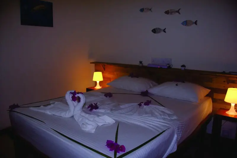 Un lit décoré de serviettes en forme de cygnes et de fleurs dans une chambre.