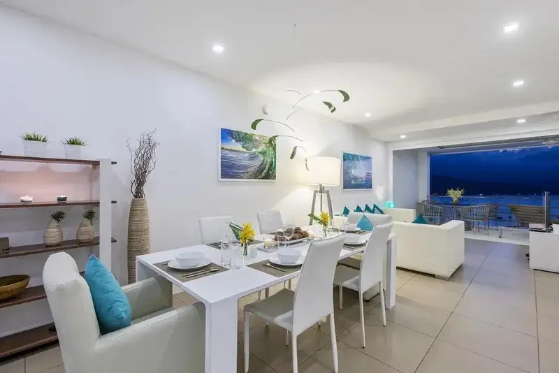 Une salle à manger lumineuse s'ouvre sur un espace salon avec vue sur la mer.