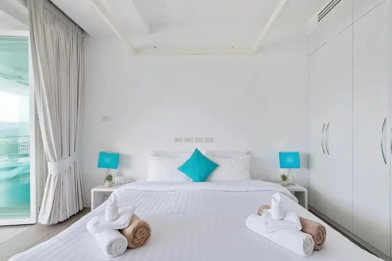 Une chambre lumineuse avec un grand lit et des rideaux blancs.