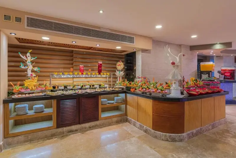 Un buffet coloré propose une variété de plats et de boissons dans une salle lumineuse.