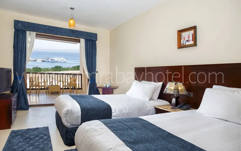 Une chambre lumineuse avec deux lits simples et vue sur la mer.