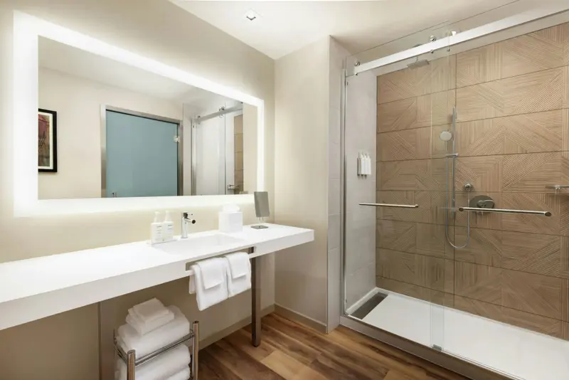 Une salle de bain moderne avec une douche vitrée et un grand miroir éclairé.