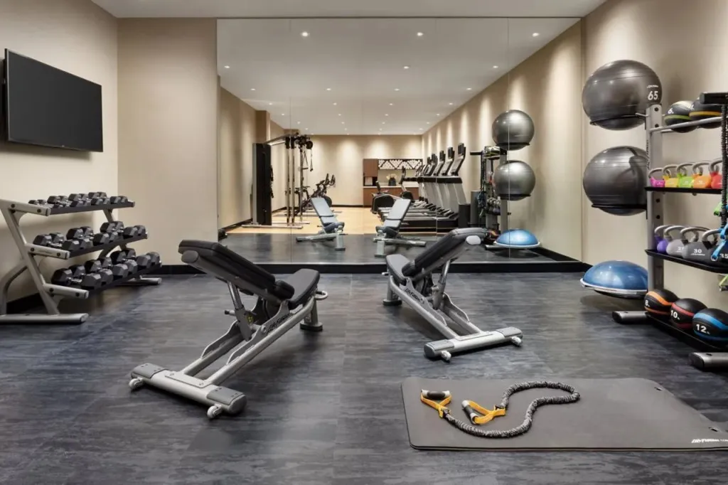 Une salle de sport lumineuse avec des équipements de musculation et des miroirs.