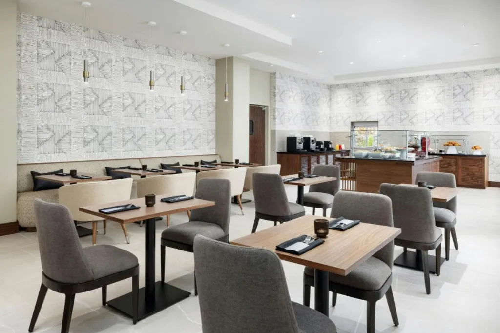 Une salle lumineuse est aménagée avec des tables et des chaises pour les repas.