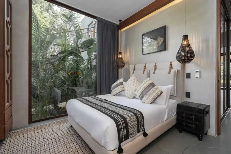 Une chambre lumineuse avec un grand lit et une vue sur la végétation.