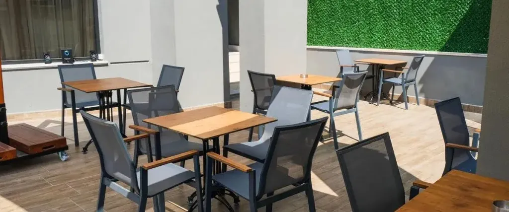 Tables et chaises disposées sur une terrasse ombragée.