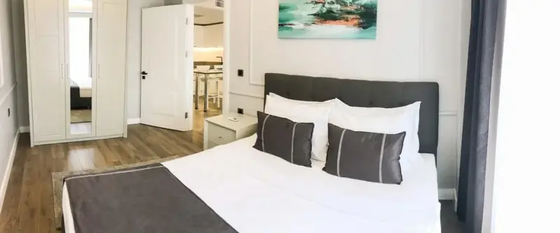Une chambre lumineuse avec un grand lit et un accès à une cuisine.
