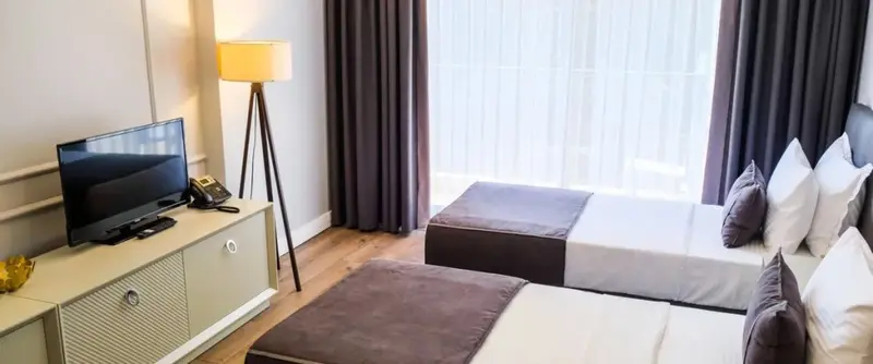 Une chambre lumineuse avec un lit double et un meuble télévision.