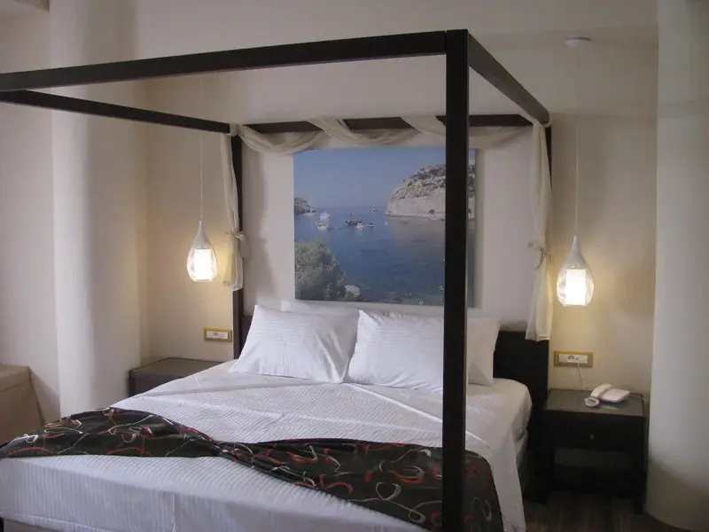 Une chambre avec un grand lit à baldaquin et une décoration murale représentant une vue sur la mer.