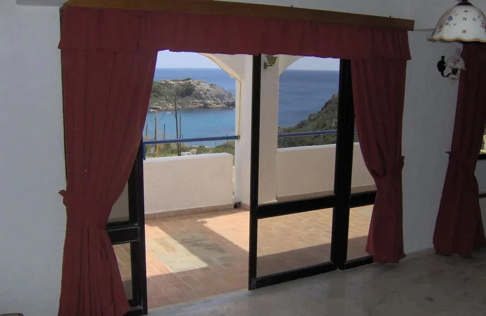 Une terrasse ensoleillée offre une vue sur la mer et les collines environnantes.