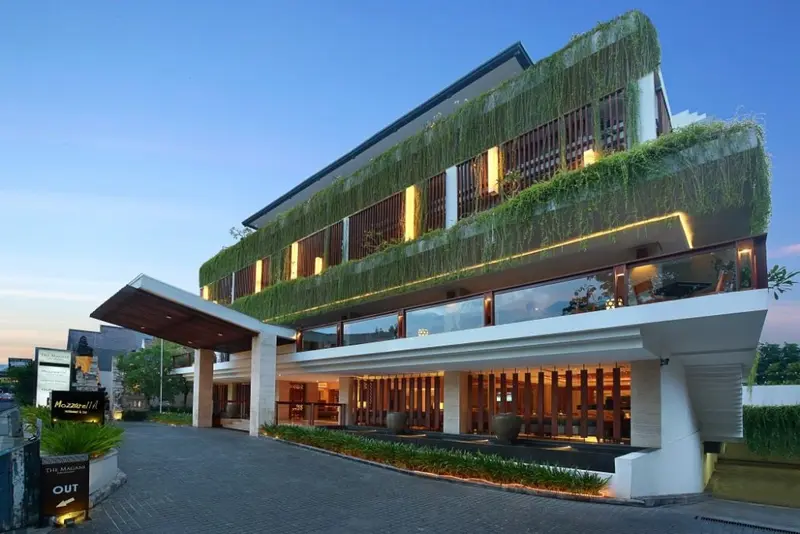 Façade moderne d'un bâtiment avec un toit végétal et une entrée illuminée.