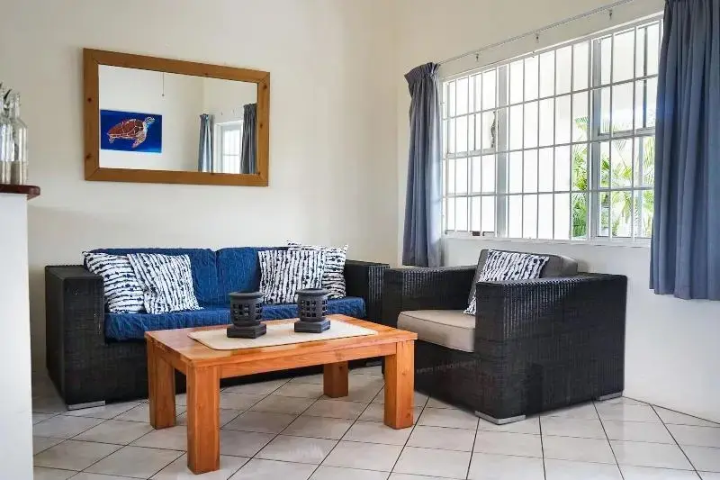 Un salon clair avec un canapé bleu et des fauteuils en rotin.