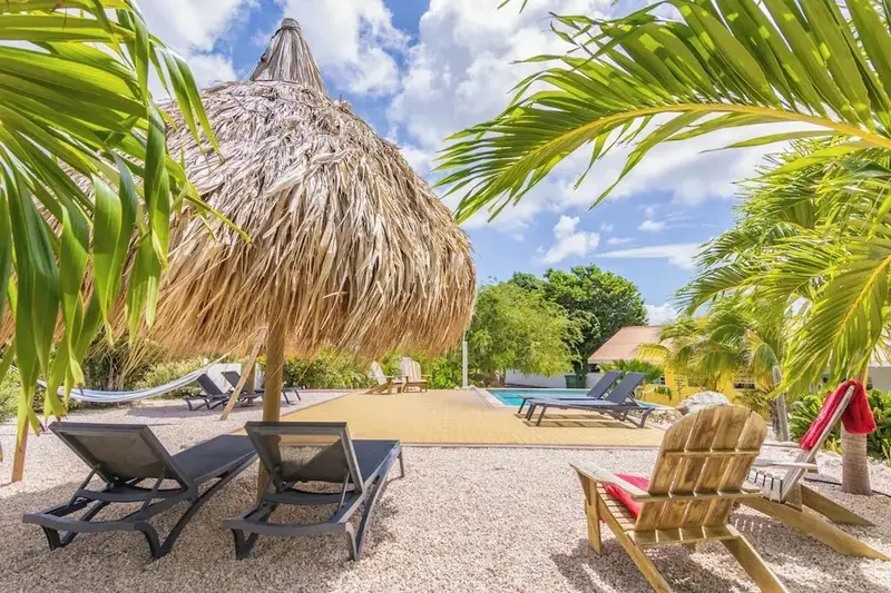 Transats et parasol en chaume bordent une piscine ensoleillée.