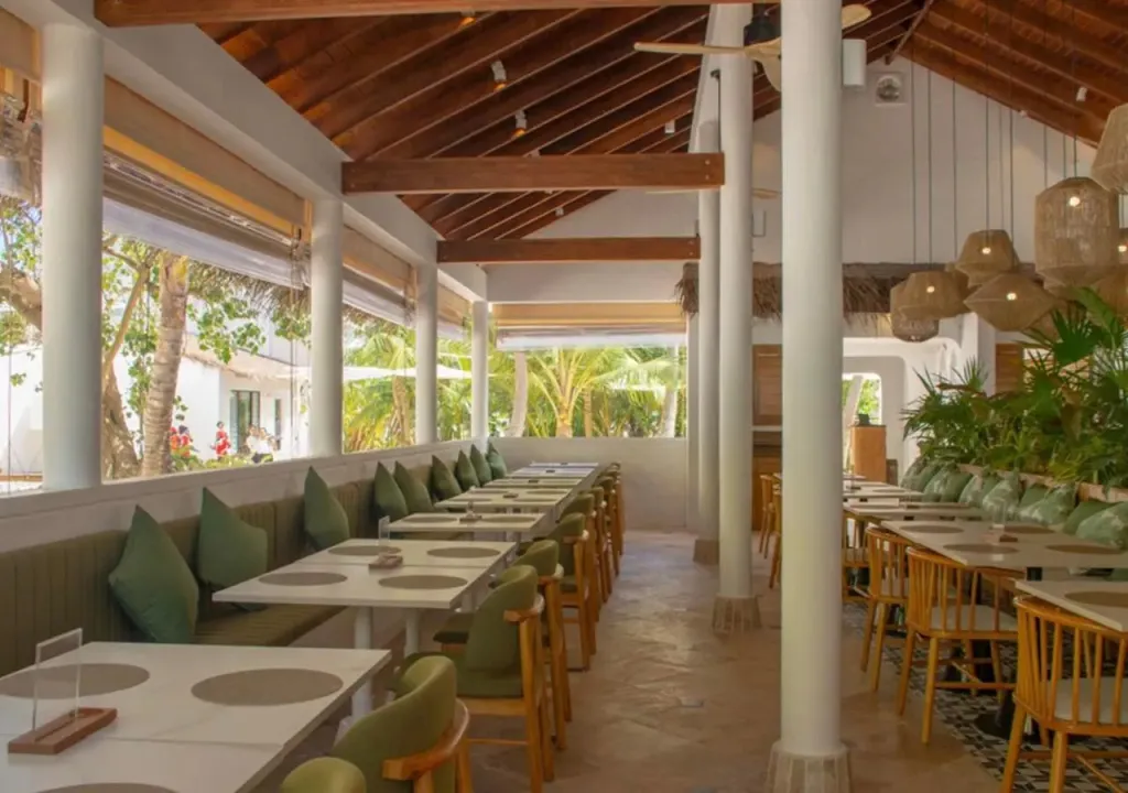 Une salle à manger lumineuse avec des tables et des banquettes vertes.