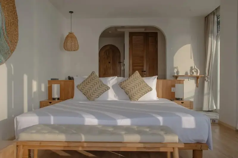Une chambre lumineuse avec un grand lit et une décoration naturelle.