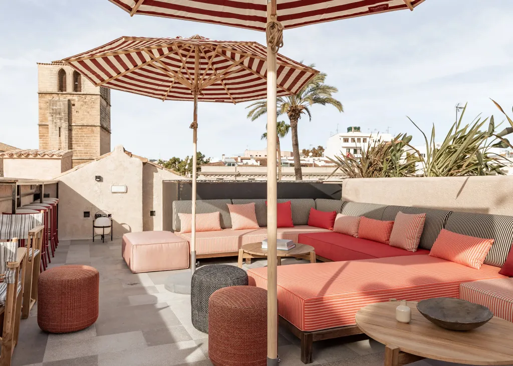 Espace de détente extérieur avec canapés et parasols rayés.