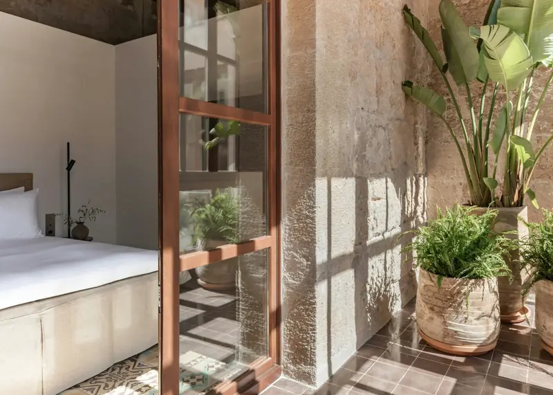 Une chambre lumineuse s'ouvre sur un espace extérieur végétalisé.