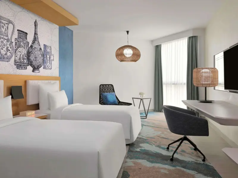 Une chambre lumineuse avec deux lits simples et un espace bureau.