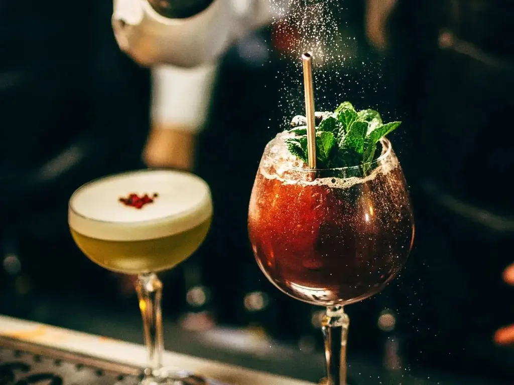 Deux cocktails colorés sont préparés au comptoir d'un bar.