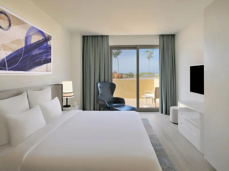 Une chambre lumineuse avec un grand lit et un accès à une terrasse.