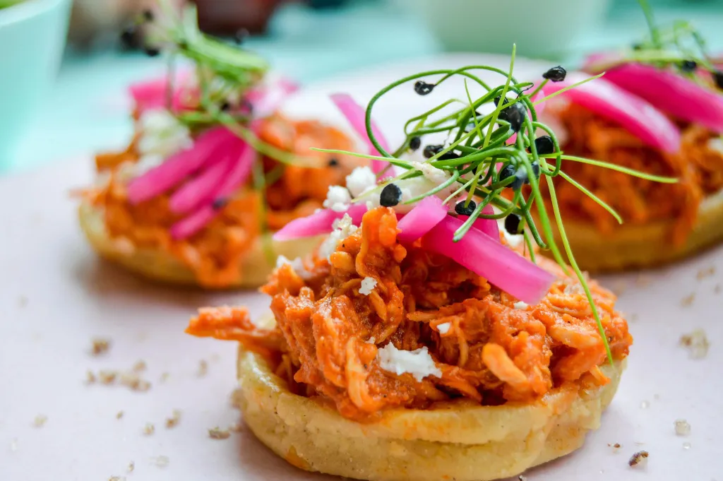 Assiettes de petites galettes garnies de viande effilochée, de légumes et d'herbes fraîches.