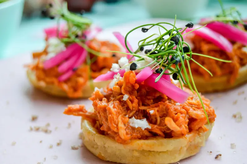 Assiettes de petites galettes garnies de viande effilochée, de légumes et d'herbes fraîches.