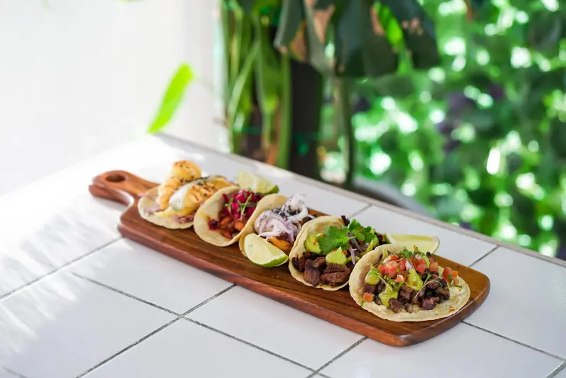 Assortiment de tacos colorés présentés sur une planche en bois.